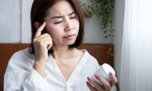 Asian woman looking at her semaglutide and thinking about how to interpret her dosing chart for semaglutide microdosing.