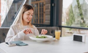 A happy woman enjoying a healthy salad and juice, representing mindful eating and making smart dietary choices while managing weight and balancing alcohol intake.