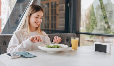 A happy woman enjoying a healthy salad and juice, representing mindful eating and making smart dietary choices while managing weight and balancing alcohol intake.