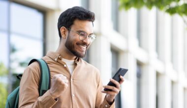 A smiling man outdoors looks excited while checking his phone, celebrating good news — representing successfully accessing a Zepbound discount or savings card.