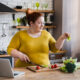 Woman preparing a healthy salad in a home kitchen, illustrating mindful eating, nutrition tracking, and strategies to overcome a weight loss plateau.