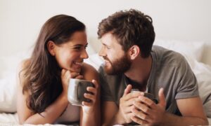 Smiling couple lying together in bed, representing intimacy and sexual health topics related to zepbound, weight loss, and sex drive changes.