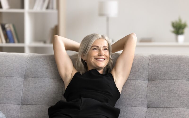 Happy woman relaxed on couch enjoying the benefits microdosing methylene blue for subtle cognitive, mood, and energy-related enhancements.