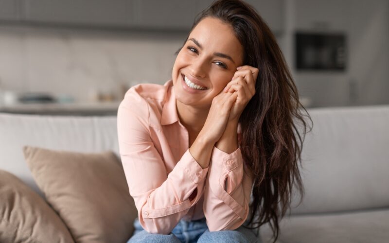 Radiant woman happy on couch because she's experiencing the positive reactions from sermorlein.