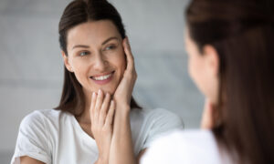 Woman examining her skin in a mirror, representing interest in collagen peptides and skin health benefits