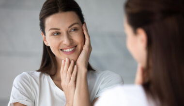 Woman examining her skin in a mirror, representing interest in collagen peptides and skin health benefits