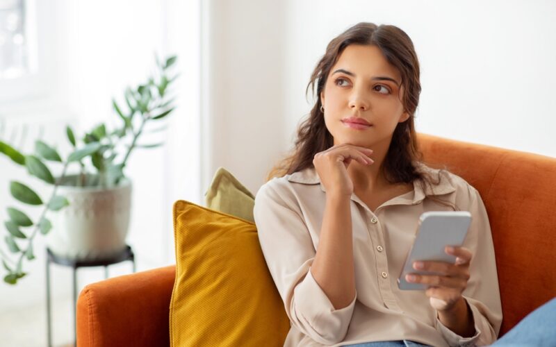 Woman deep in thought sitting on couch researching different weight loss pens and how they work