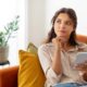 Woman deep in thought sitting on couch researching different weight loss pens and how they work
