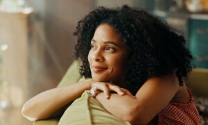 Woman who started taking Sermorelin on couch calming herself after feeeling anxiety or restlessness.