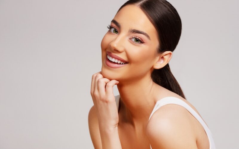 Beautiful smiling woman with healthy, shiny hair and glowing skin, representing the potential benefits of vitamin B12 for hair and skin health