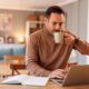 Man working on a laptop at home while drinking coffee, representing early-stage Mounjaro (tirzepatide) weight loss progress and lifestyle changes during the first three months of treatment.