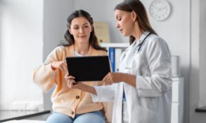 Doctor showing a patient information on an iPad, patient looks happy and engaged, representing guidance on safe GLP-1 medication dosing and personalized care.