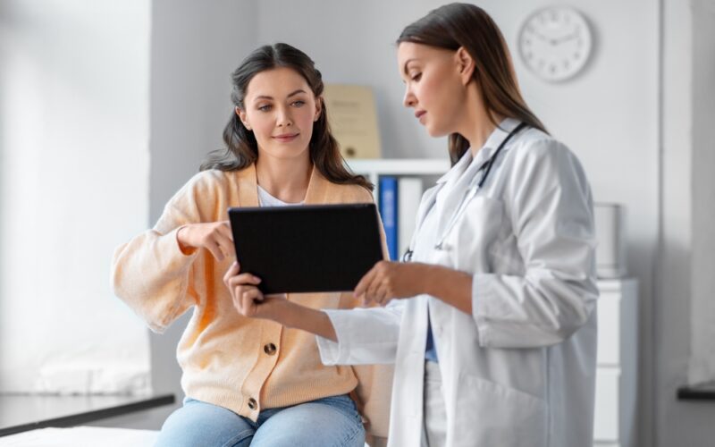 Doctor showing a patient information on an iPad, patient looks happy and engaged, representing guidance on safe GLP-1 medication dosing and personalized care.