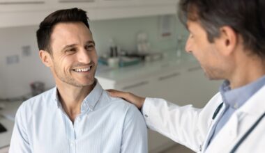 Doctor speaking reassuringly with a male patient in a medical office, representing a supportive conversation about erectile dysfunction diagnosis and treatment options