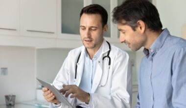 Male doctor showing a male patient information on an iPad, discussing hormonal health, testosterone levels, thyroid function, and treatment options for hormonal imbalance.