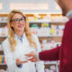 Pharmacist handing a medication container to a customer, representing questions about compounded semaglutide safety, legality, and pharmacy dispensing.