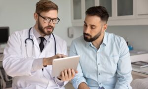 A healthcare provider reviewing treatment information on a tablet with a patient in a clinic, representing discussion of retatrutide and next-generation weight loss therapies.