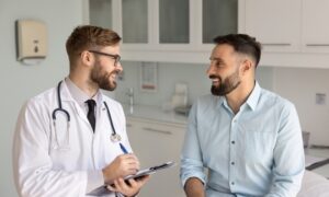 A doctor talking with a male patient during a first weight loss lab visit, discussing symptoms and lab testing.