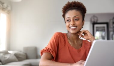 Woman smiling while using a laptop at home, learning about Mounjaro dosing schedule and tirzepatide titration for weight loss and diabetes management.