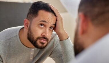 Man looking at his reflection. Worried about hair loss or thinning