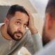 Man looking at his reflection. Worried about hair loss or thinning