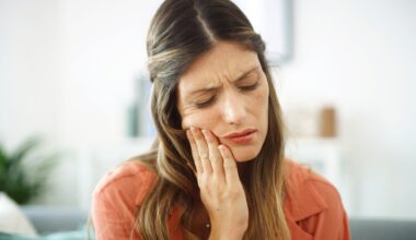 Woman feeling her mouth for tooth pain, possibly caused by ozempic teeth decay.
