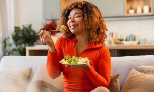 Young african american woman eating green salad, having a healthy meal after she stopped taking wegovy