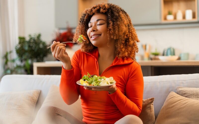 Young african american woman eating green salad, having a healthy meal after she stopped taking wegovy